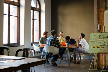 Creative business people working at tables in sunny office