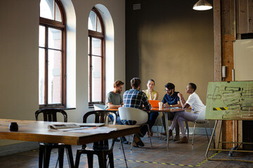 Creative business people working at tables in sunny office