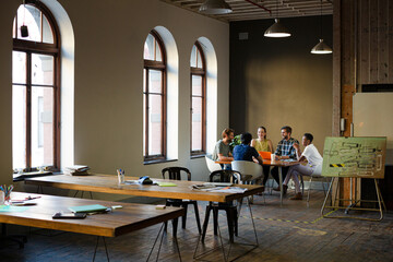 Creative business people working at tables in sunny office