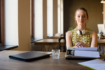 Creative businesswoman reviewing paperwork at typewriter in office