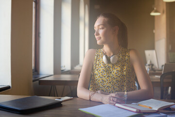 Portrait smiling casual businesswoman headphones in sunny open office