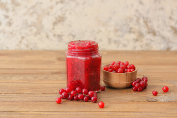 Jar of red currant jam and berries on wooden table