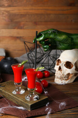 Woman putting straw into shot with tasty bloody Mary cocktail on wooden background
