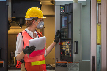 machine control worker at control panel operating CNC lathe machine in metalwork workshop