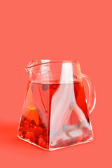 Jug of tasty tea with cranberry on color background