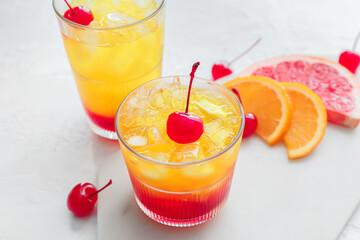 Glasses of tasty Tequila Sunrise cocktail on light background