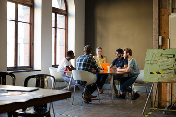 Creative business people working at tables in sunny office