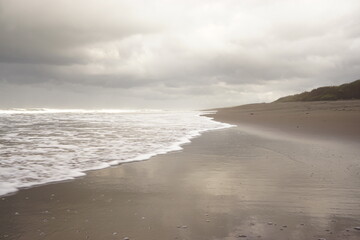 Soft waves of the sea on a sandy beach on a cloudy sky background. landscape beach
