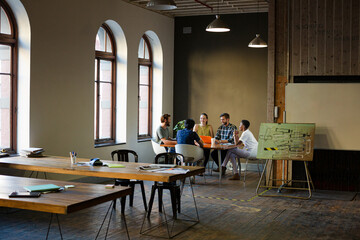 Creative business people working at tables in sunny office