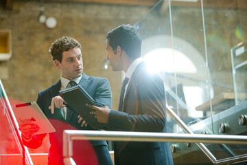 Businessmen using tablet computer outside conference room