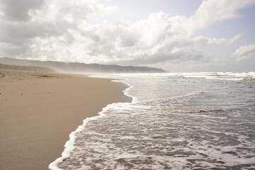 Soft waves of the sea on a sandy beach on a cloudy sky background. landscape beach