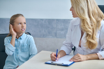 Fototapeta premium Girl with poor hearing at otolaryngologists appointment