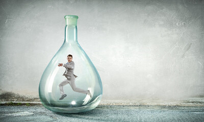 Young businessman dancing inside glass bottle
