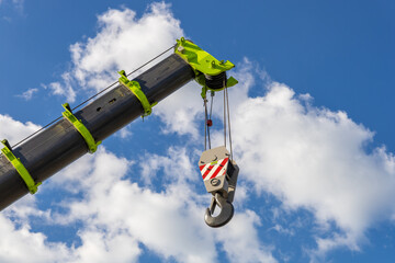 Telescopic boom of a mobile crane with a hook against a cloudy sky. Construction and repair equipment for lifting loads © hodim