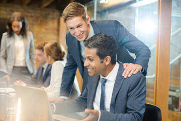 Businessmen using laptop in conference room