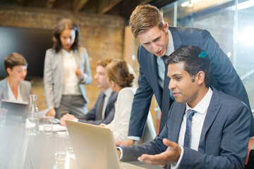 Businessmen using laptop in conference room