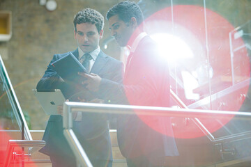 Businessmen using tablet computer outside conference room