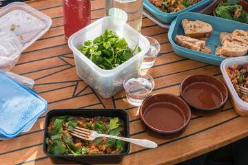 A picnic dinner on a motorboat during summer with salad and rice and beans.
