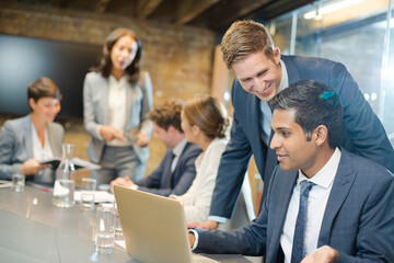 Businessmen using laptop in conference room