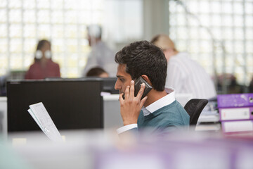Smiling businessman talking on cell phone in office