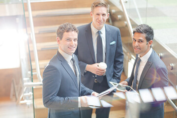 Businessmen with digital tablet and coffee talking on stairs