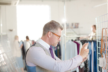 Naklejka na ściany i meble Fashion designer examining clothing on racks