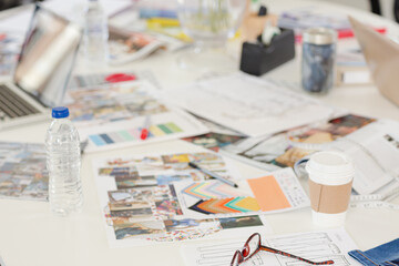 Laptop, swatches, proofs and paperwork on desk in fashion desk office