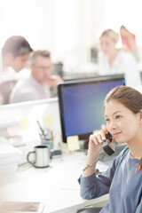 Smiling businesswoman talking on telephone in office