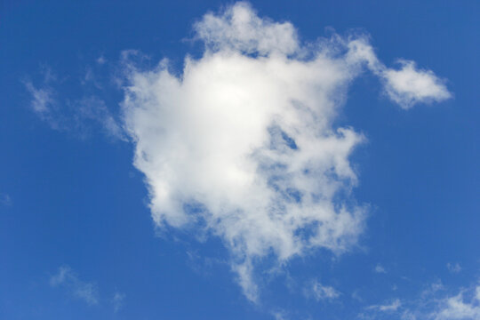A white fluffy cloud drifts through a dreamy blue sky