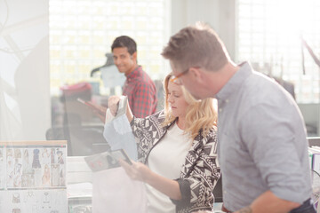 Fashion designers discussing fabric swatch in sunny office