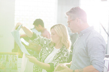 Obraz premium Fashion designers discussing fabric swatch in sunny office