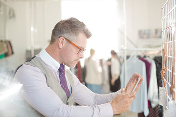 Fototapeta premium Fashion designer examining clothing on racks