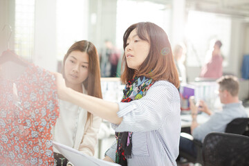 Fashion designers examining clothing on racks