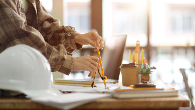 Closeup, engineer architecture using divider compass to measuring building scale on blueprint