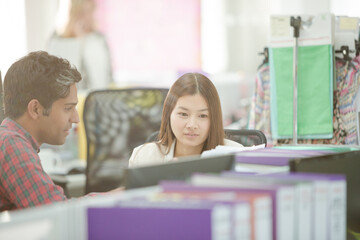 Fashion designers talking at desk in office