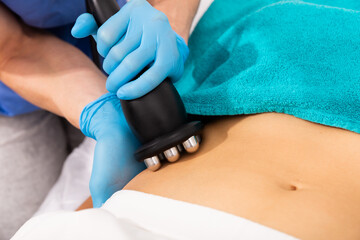 Fototapeta premium Closeup of female abdomen during professional ultrasonic fat cavitation procedure in cosmetology clinic