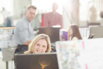 Portrait smiling fashion designer drinking coffee at computer in office