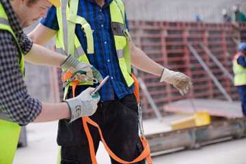 Construction worker fastening coworker&sbquo;&Auml;&ouml;&radic;&Ntilde;&radic;&yen;s safety harness