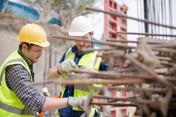 Construction worker fastening coworker‚Äö√Ñ√¥s safety harness