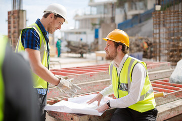 Construction worker engineer reviewing blueprints at highrise construction site