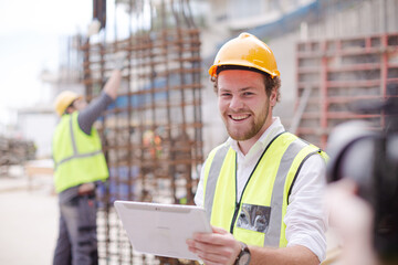 Portrait confident construction worker digital tablet at construction site