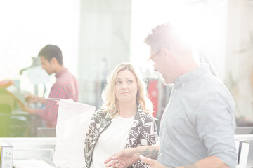 Fashion designers discussing fabric swatch in sunny office