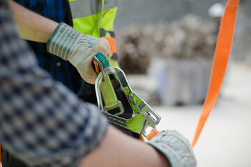 Construction worker fastening coworker‚Äö√Ñ√¥s safety harness