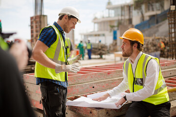 Construction worker engineer reviewing blueprints at highrise construction site