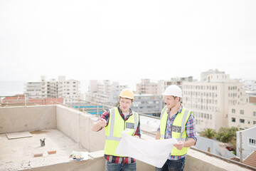 Construction worker engineer reviewing blueprints at highrise construction site