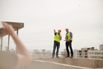 Construction worker and engineer talking at highrise construction site