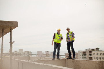 Construction worker and engineer talking at highrise construction site