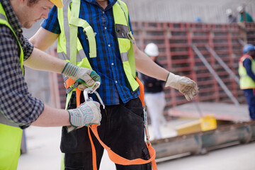 Construction worker fastening coworker&sbquo;&Auml;&ouml;&radic;&Ntilde;&radic;&yen;s safety harness