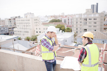 Construction worker engineer reviewing blueprints at highrise construction site