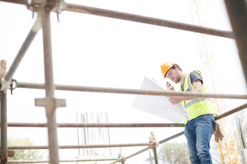 Engineer reviewing blueprints at high rise construction site